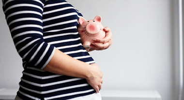 Pregnant woman holding a piggy bank
