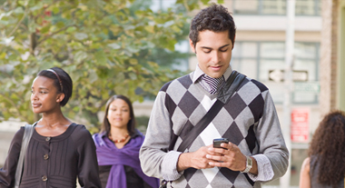 Person using cell phone while walking down a busy street