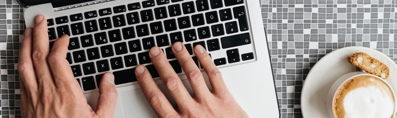 Hands typing on keyboard with coffee