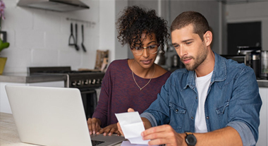 Couple using laptop and reading receipts