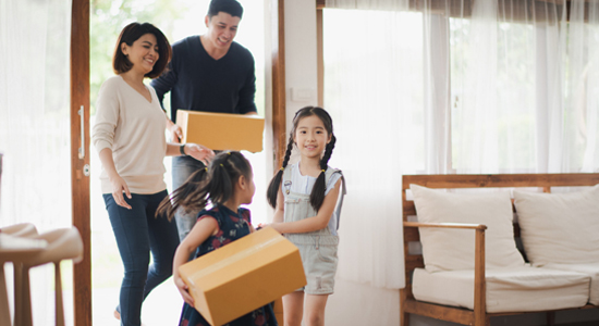 Family carrying boxes into house