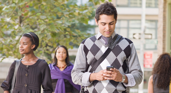 Person using cell phone while walking down a crowded street