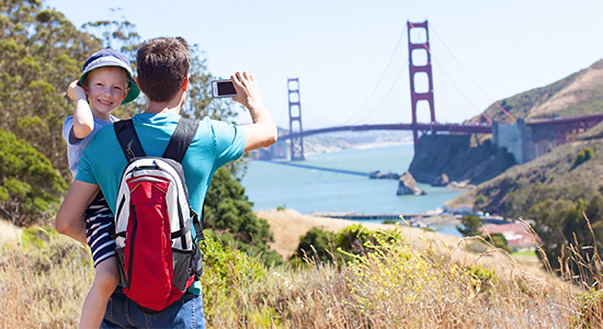 Parent holding child while taking a photo of the Golden Gate Bridge