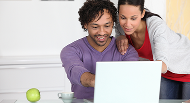 Couple checking investments on laptop at home