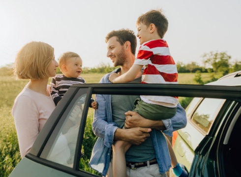 Young family of four near car